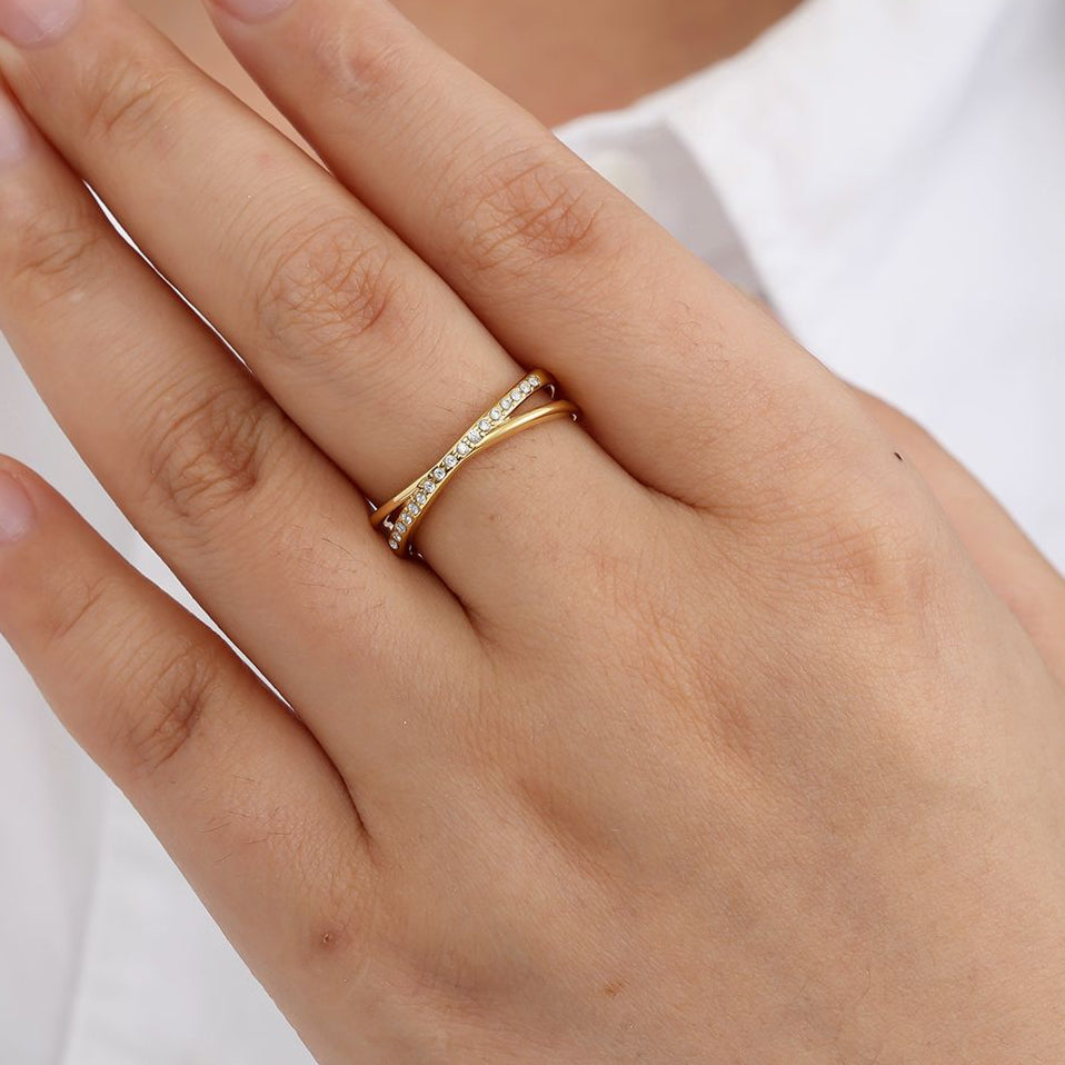 Edelstahlring überkreuzt in gold mit Zirkon-Steinen, größenverstellbar.